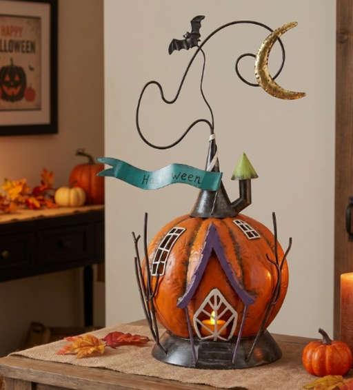 Decorative Halloween pumpkin with house design and candle inside, placed on a table.