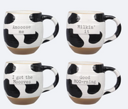 Set of four cow print mugs with humorous sayings on a white background