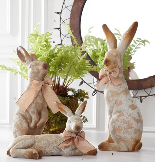 Decorative rabbits with lace patterns and bows in front of a plant.