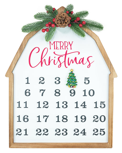 A house-shaped wooden advent calendar with a white face, gray numbers, pink 'Merry Christmas' lettering, a small green ornament, and pine branches with red berries at the top.