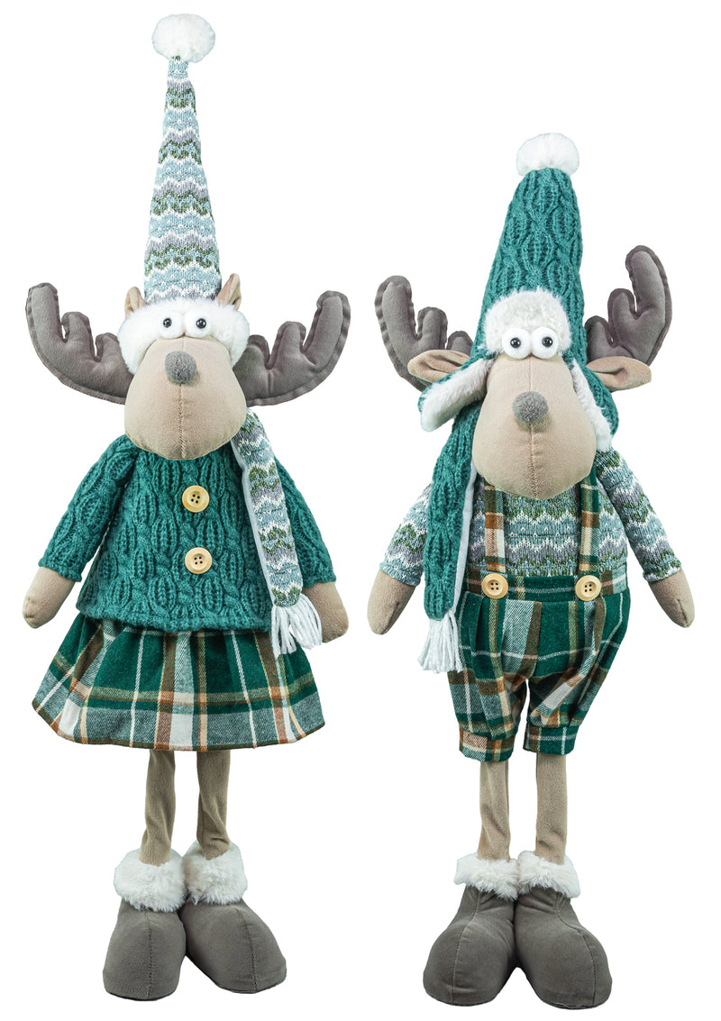 Two plush moose holiday decorations standing side by side on a white background. One wears a teal sweater and plaid skirt, and the other wears matching green plaid overalls with a teal knit hat and scarf.