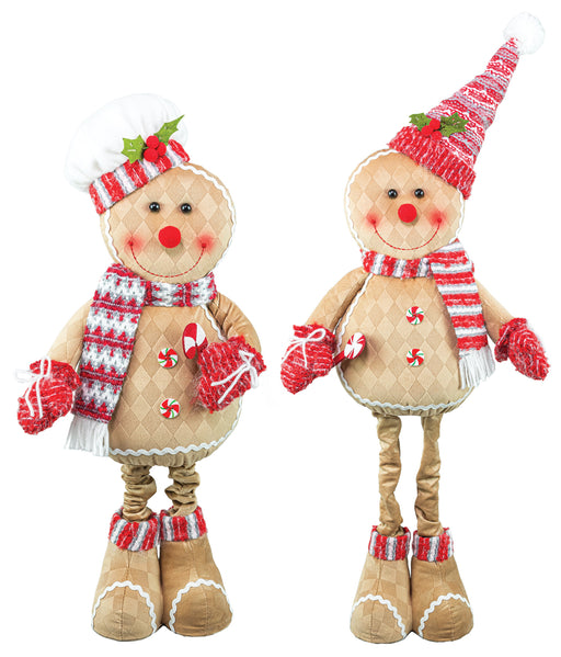 Two Christmas gingerbread-themed plush dolls standing side by side on a plain white background. One doll is dressed as a gingerbread man with a striped red and white hat, scarf, mittens, and candy cane accents, while the other is a gingerbread cookie with a red and white striped Santa hat, scarf, mittens, and boots.