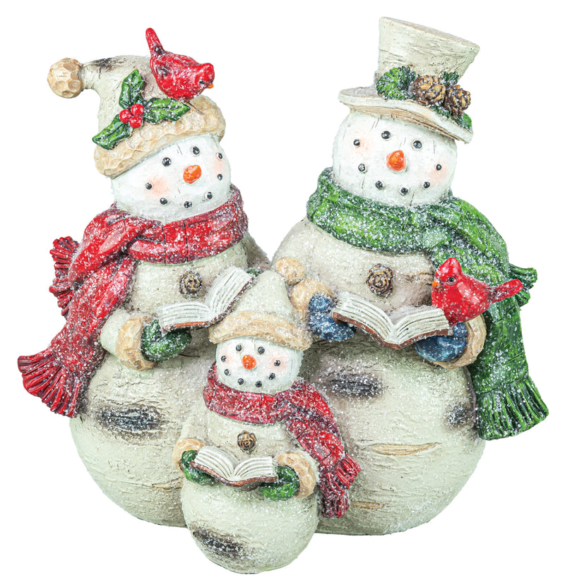 Three snowman figurines decorated for Christmas, including two larger snowmen and one smaller one, wearing winter hats, scarves, and holding open books, with red birds on their hats. The snowmen have a textured off-white finish with green, red, and blue accents.