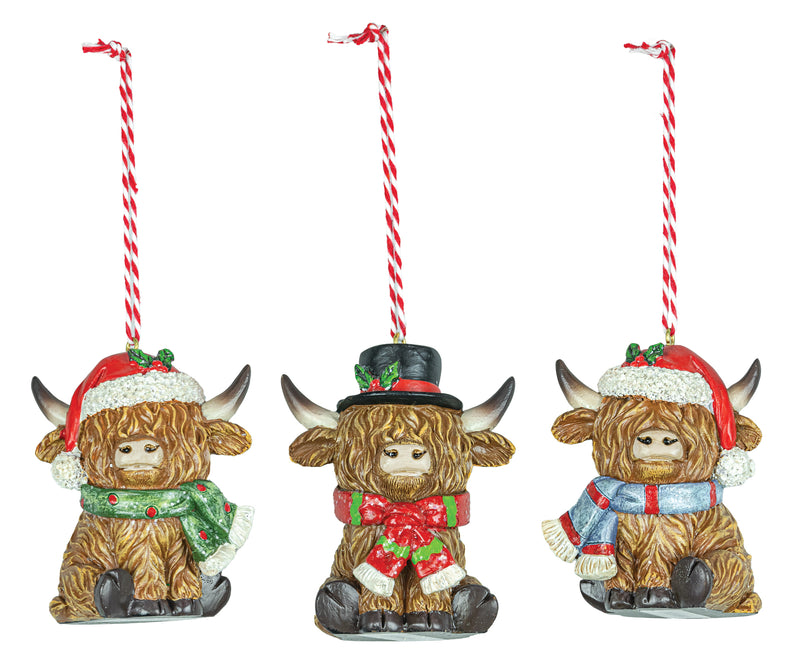 Three decorative Highland cow ornaments with festive attire on a white background