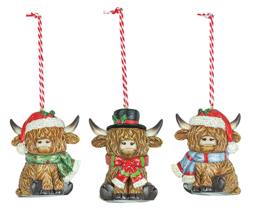 Three decorative Highland cow ornaments with festive attire on a white background