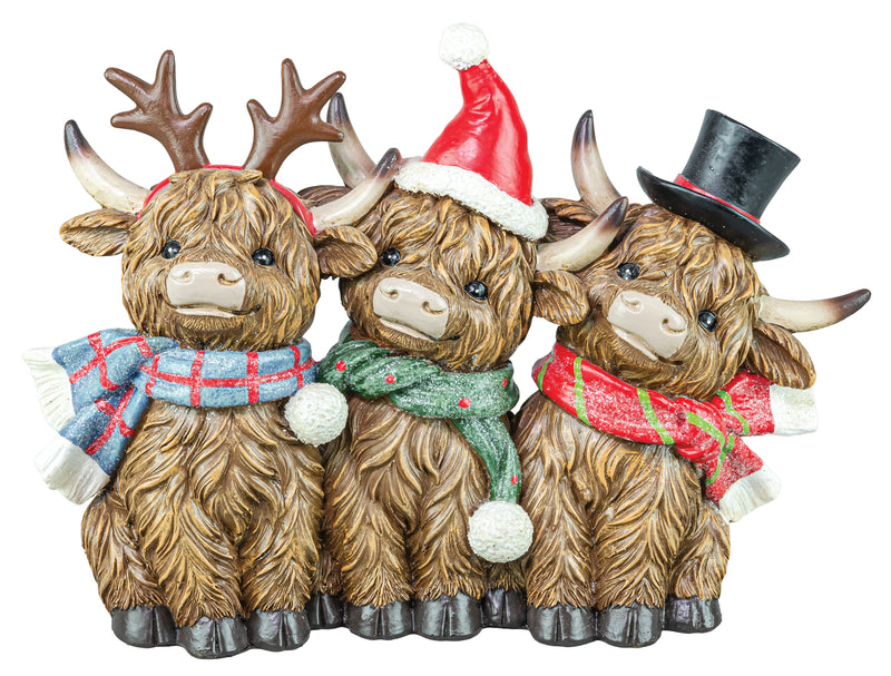 Three Highland cow figurines decorated for Christmas, wearing antlers, a Santa hat, and a top hat, with plaid scarves in blue, green, and red.