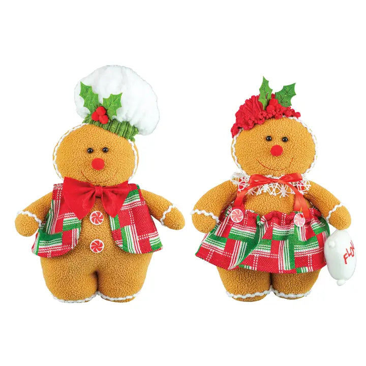 Two Christmas gingerbread plush dolls on a white background. One doll wears a white chef's hat with holly and wears a red bow and plaid vest.