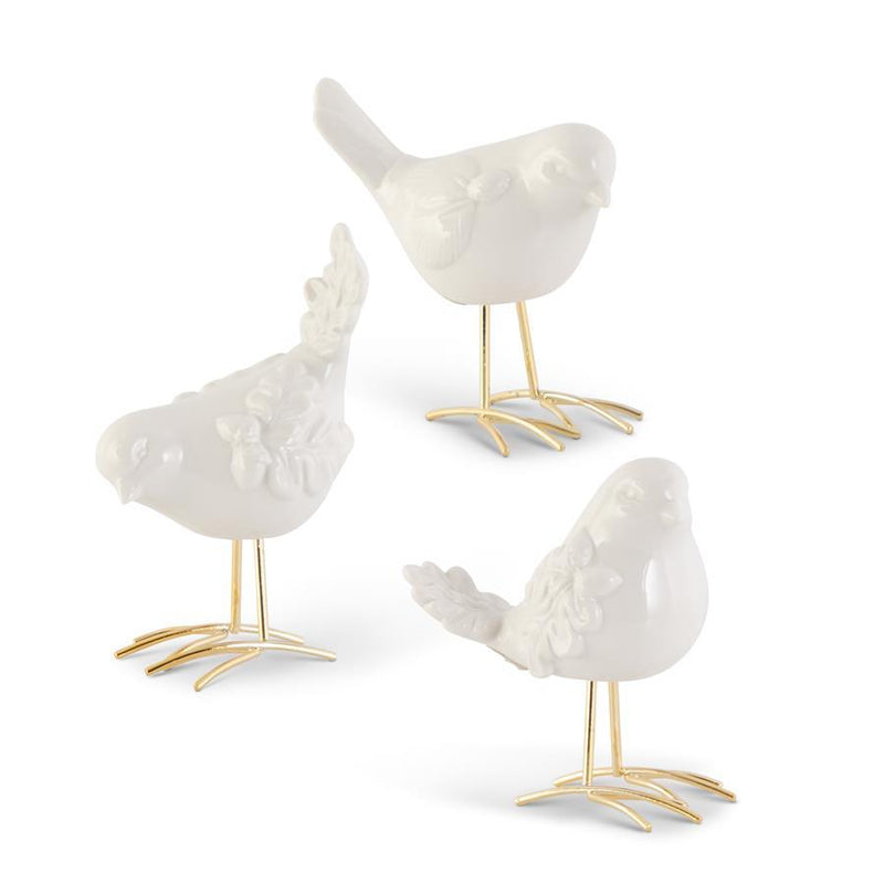 Three white ceramic birds with gold legs on a white background