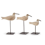 Three decorative bird figures on stands against a white background