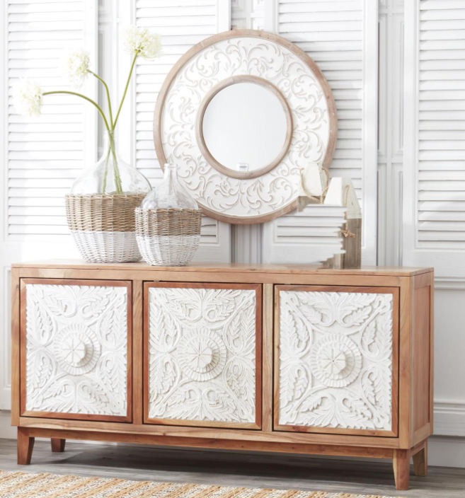 Wooden sideboard with decorative white panels and a round mirror above it.