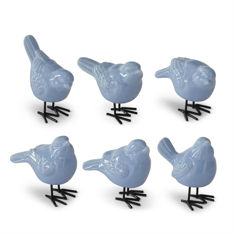 Set of six blue ceramic bird figurines on black stands against a white background