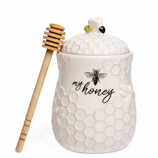 White honey jar with honeycomb design and a wooden dipper on a white background