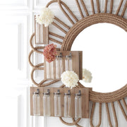 Decorative wall mirror with floral arrangements and glass bottles on a white background