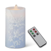 Flickering LED candle with floral design and remote control on a white background
