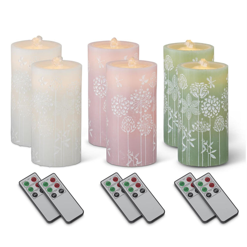 Set of six decorative candles with floral patterns and four remote controls on a white background
