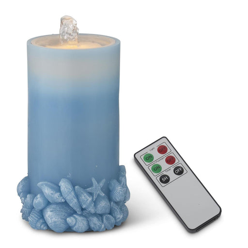 Blue candle with seashell decorations and a remote control on a white background