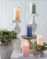 Decorative candles on small stands with a textured white wall background
