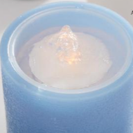 Blue candle with a white wick on a white background