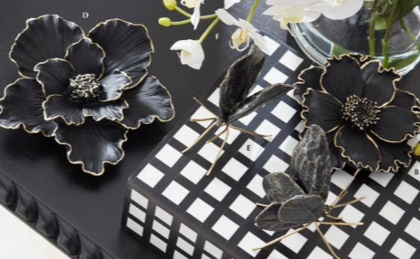 Black floral brooches on a checkered surface with flowers in the background
