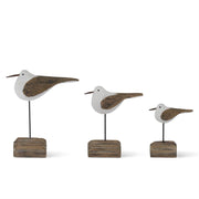 Three decorative bird figures on wooden stands against a white background