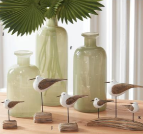 Decorative ceramic birds on stands with green ceramic vases in the background