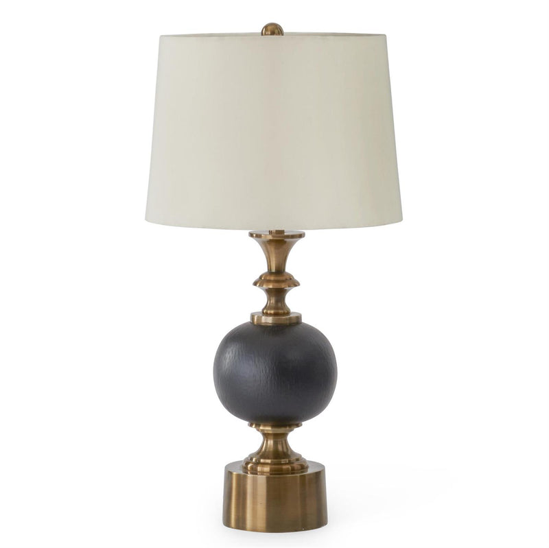 A table lamp with a tapered off-white fabric shade, a textured dark gray spherical base, and an antique brass-finished metal neck and pedestal base, shown on a plain white background.