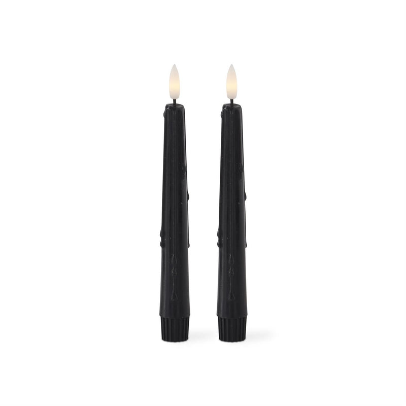 Two black candles with wicks on a white background