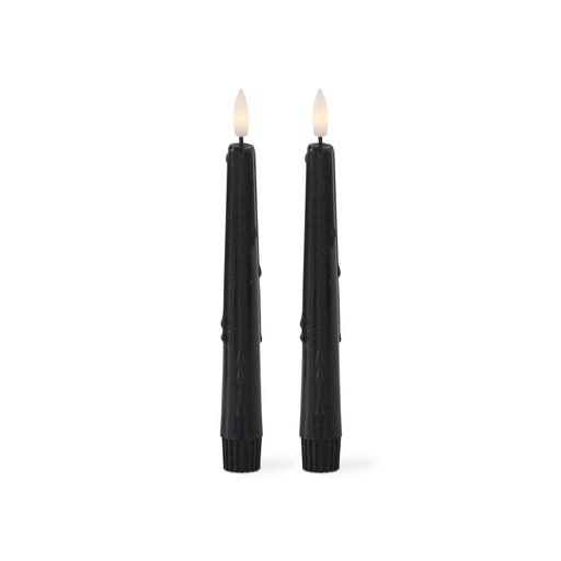Two black candles with wicks on a white background