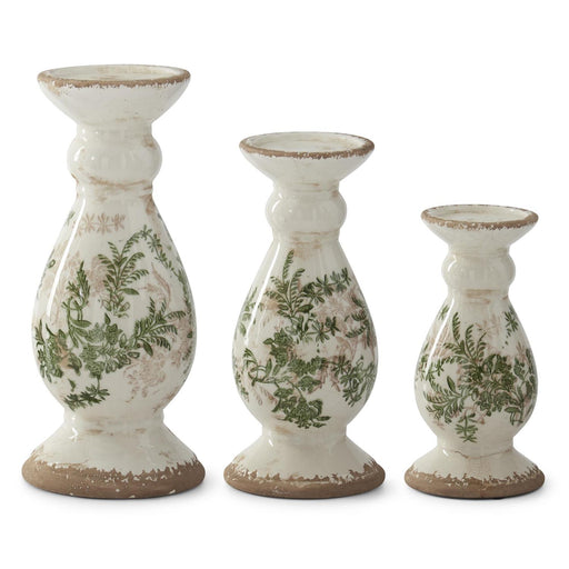 Three white candle holders with green leaf patterns on a white background