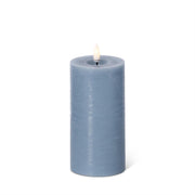 Blue candle with a white wick on a white background