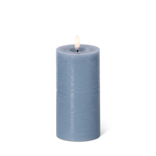 Blue candle with a white wick on a white background