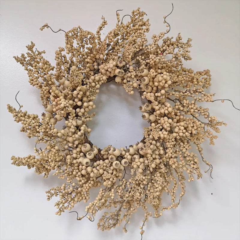 A round dried floral wreath made of beige berries and twig branches, photographed against a plain light background.