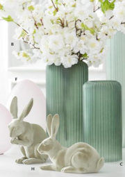 Two white rabbit figurines with a green vase and white flowers in the background.
