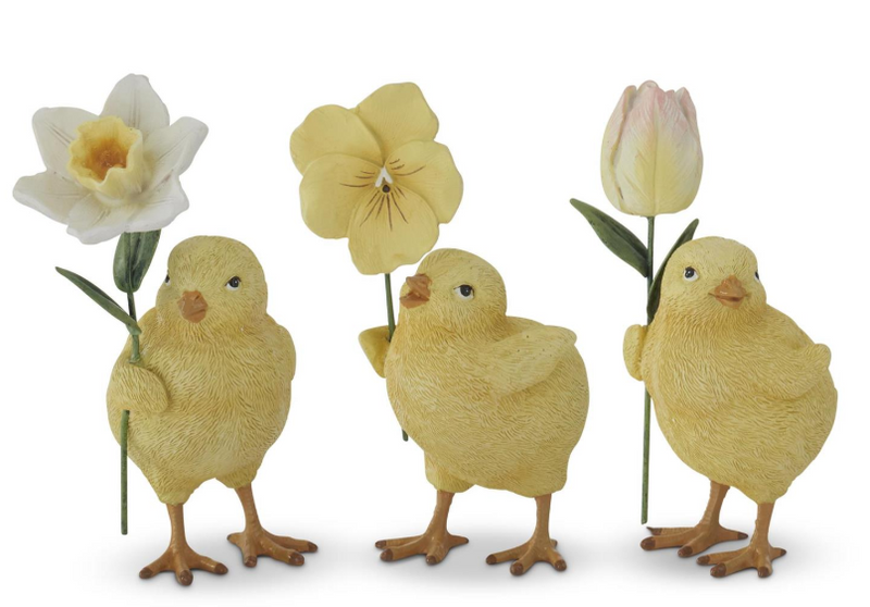 Three yellow chick figurines holding flowers on a white background