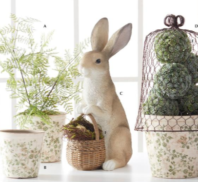 Decorative scene with a plush rabbit, basket, and potted plants on a white surface.