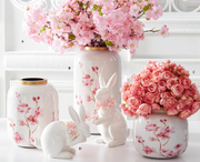 Decorative vases and rabbit figurines with floral designs on a white surface.