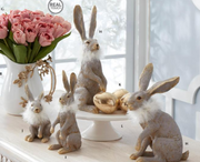 Decorative rabbits and a bouquet of pink tulips on a white surface.