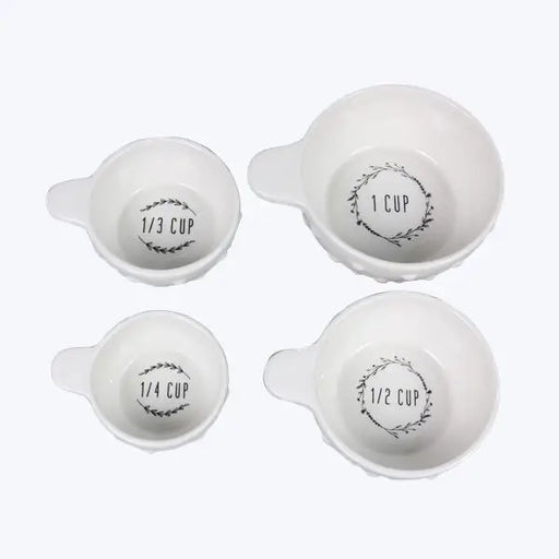 Set of four white measuring cups with black text on a white background
