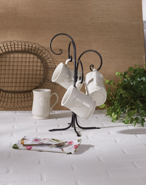 White mugs hanging from a decorative metal stand on a kitchen counter.