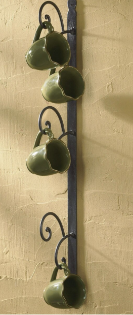Decorative wall hanging with green ceramic cups on a beige wall
