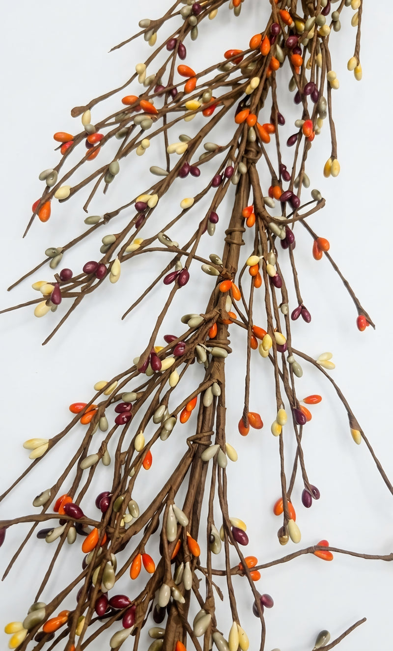 Autumn berry garland with brown branches, small orange berries, and cream and burgundy buds, photographed against a plain white background.