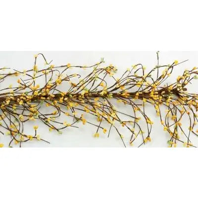 A decorative artificial flowering branch with thin brown twigs, small yellow blossoms, and a few pale green buds, laid horizontally on a plain white background.