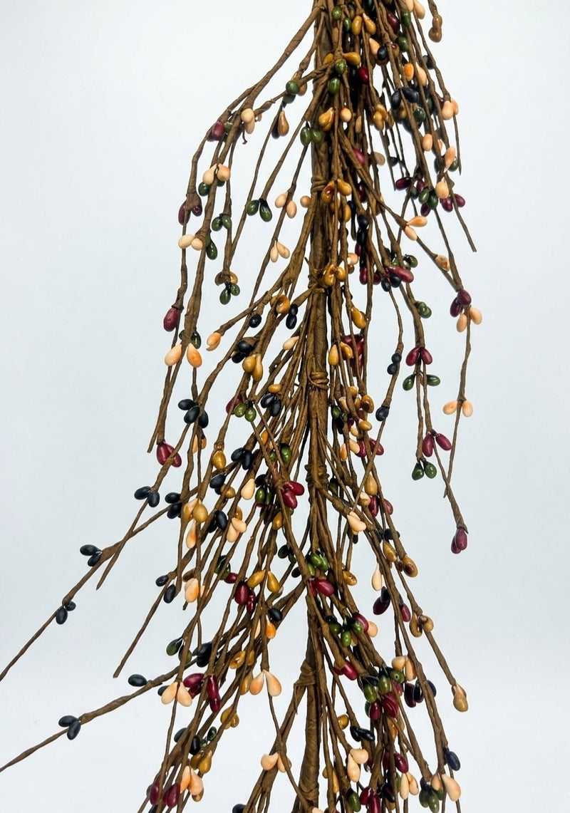 A dried botanical arrangement of slender brown branches covered with small, multi-colored berries in shades of red, yellow, green, and black, set against a solid light gray background.