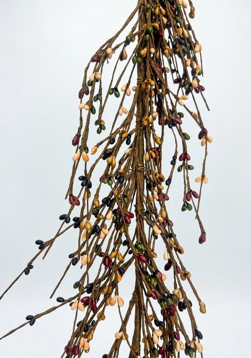 A dried botanical arrangement of slender brown branches covered with small, multi-colored berries in shades of red, yellow, green, and black, set against a solid light gray background.