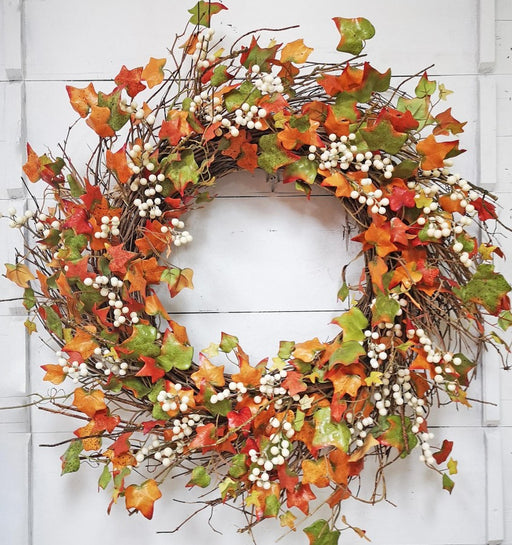 Autumn wreath with colorful leaves and berries on a white wooden background