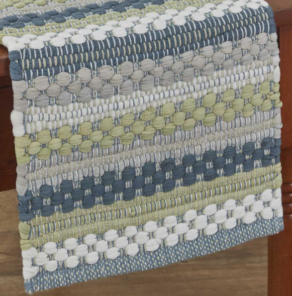 A close-up of a woven textile runner draped over a wooden chair, featuring horizontal stripes of blue, gray, beige, and light olive green with raised circular texture details.