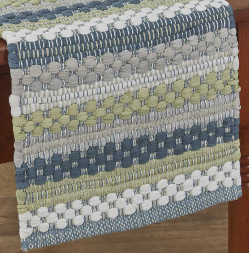 A close-up of a woven textile runner draped over a wooden chair, featuring horizontal stripes of blue, gray, beige, and light olive green with raised circular texture details.