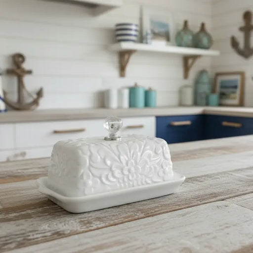 White ceramic butter dish on a wooden surface with a kitchen background