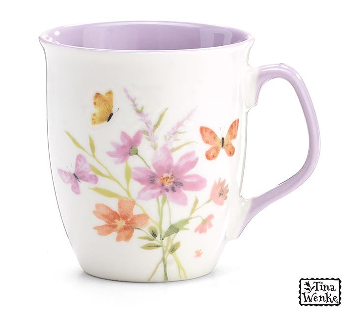 A white ceramic mug with a light purple interior and handle, decorated with a watercolor floral pattern of pink and orange flowers, green stems, and yellow butterflies. The brand name 'Tina Wenke' is visible in a logo in the bottom right corner.