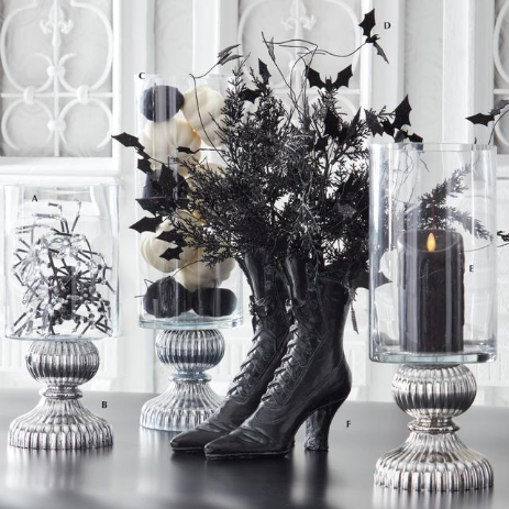 Decorative setup with black boots, candles, and foliage on a table.